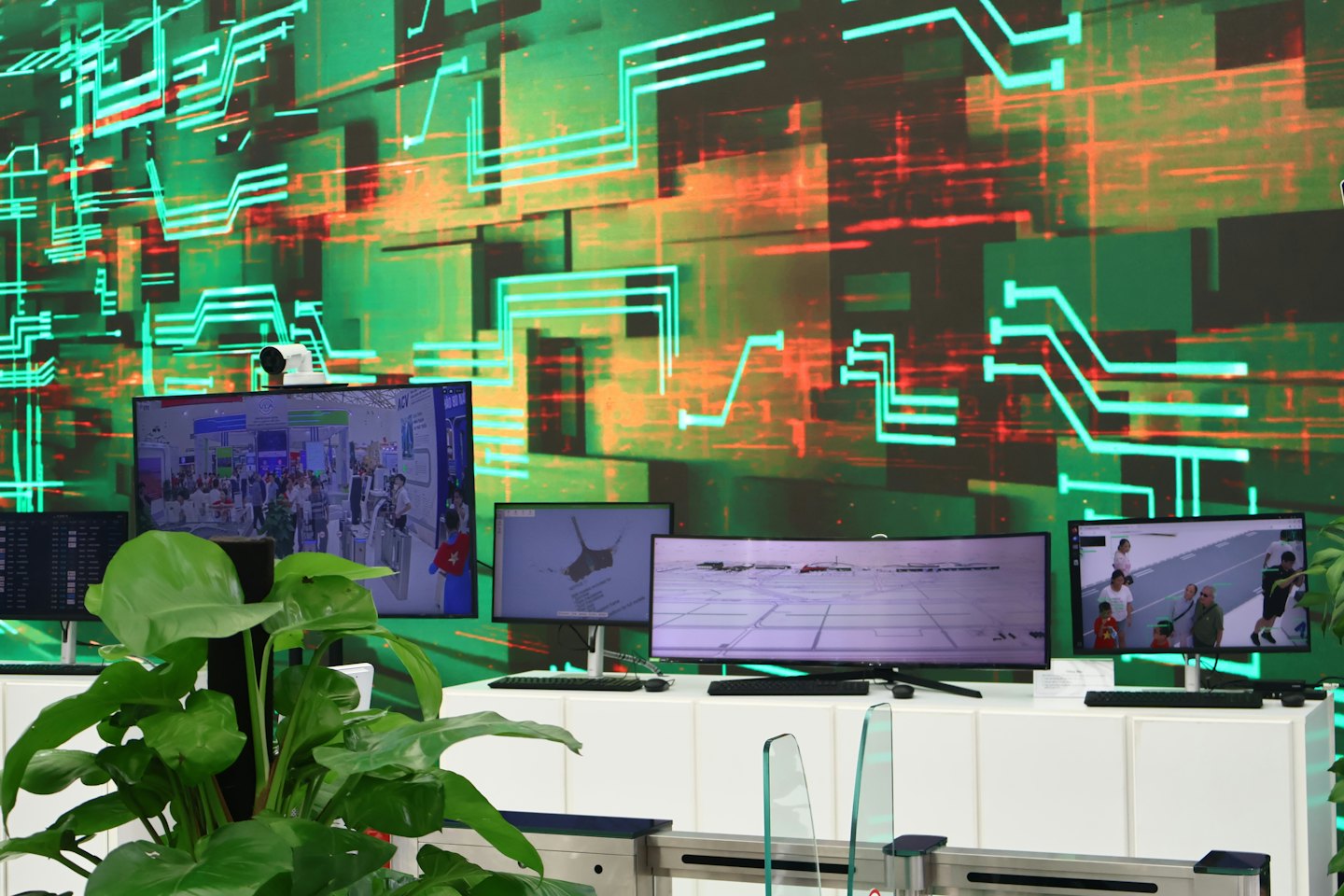 Diverse schermate digitali mostrano filmati di sicurezza e mappe in una sala di controllo.