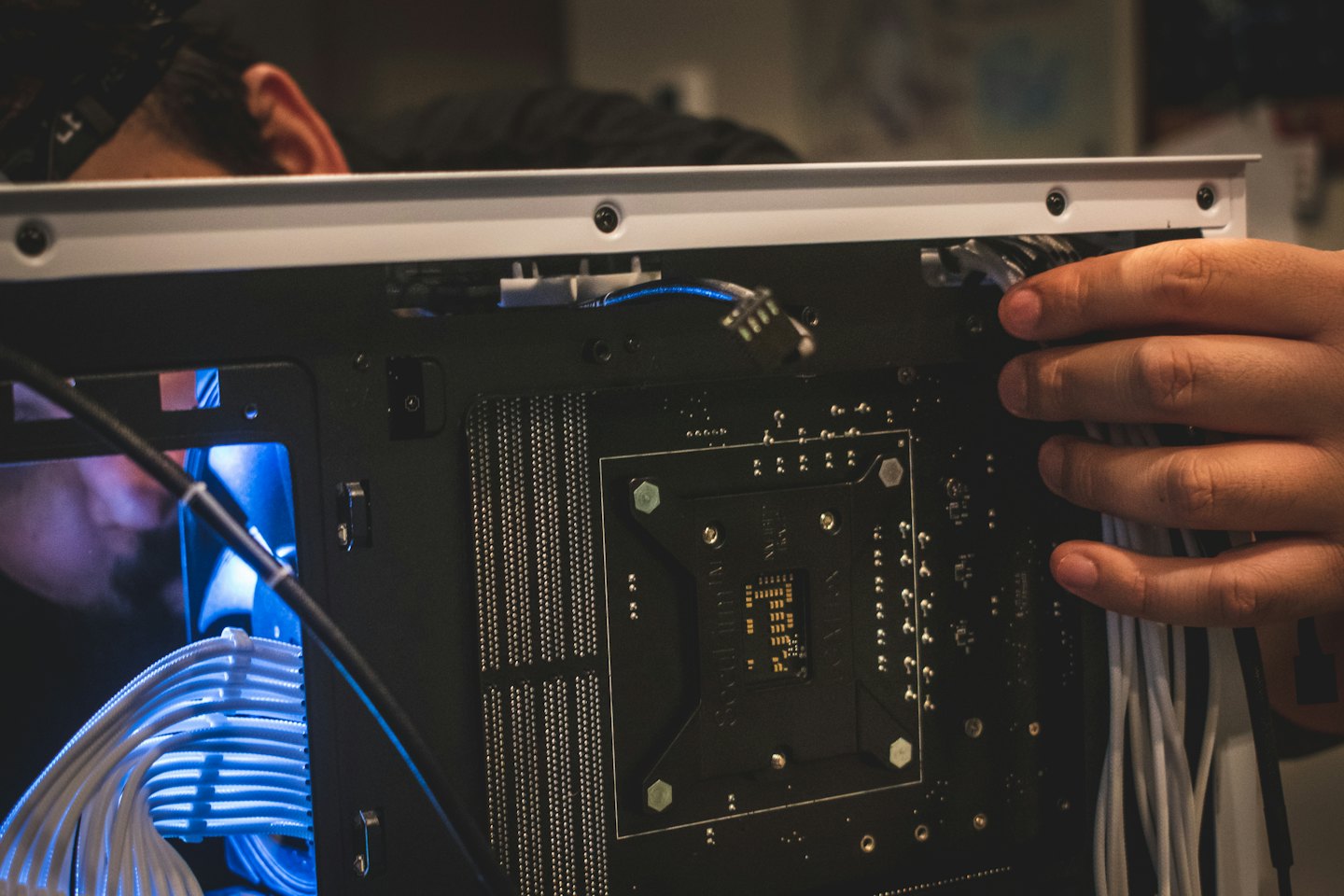 Tecnico che organizza cavi bianchi all'interno di un case per computer.