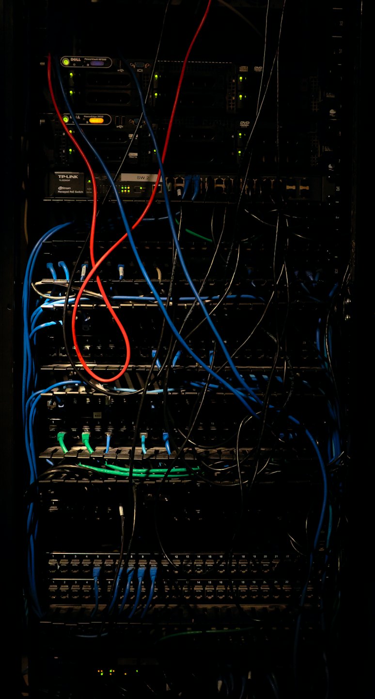 Armadio rack con cavi di rete blu e rossi aggrovigliati.