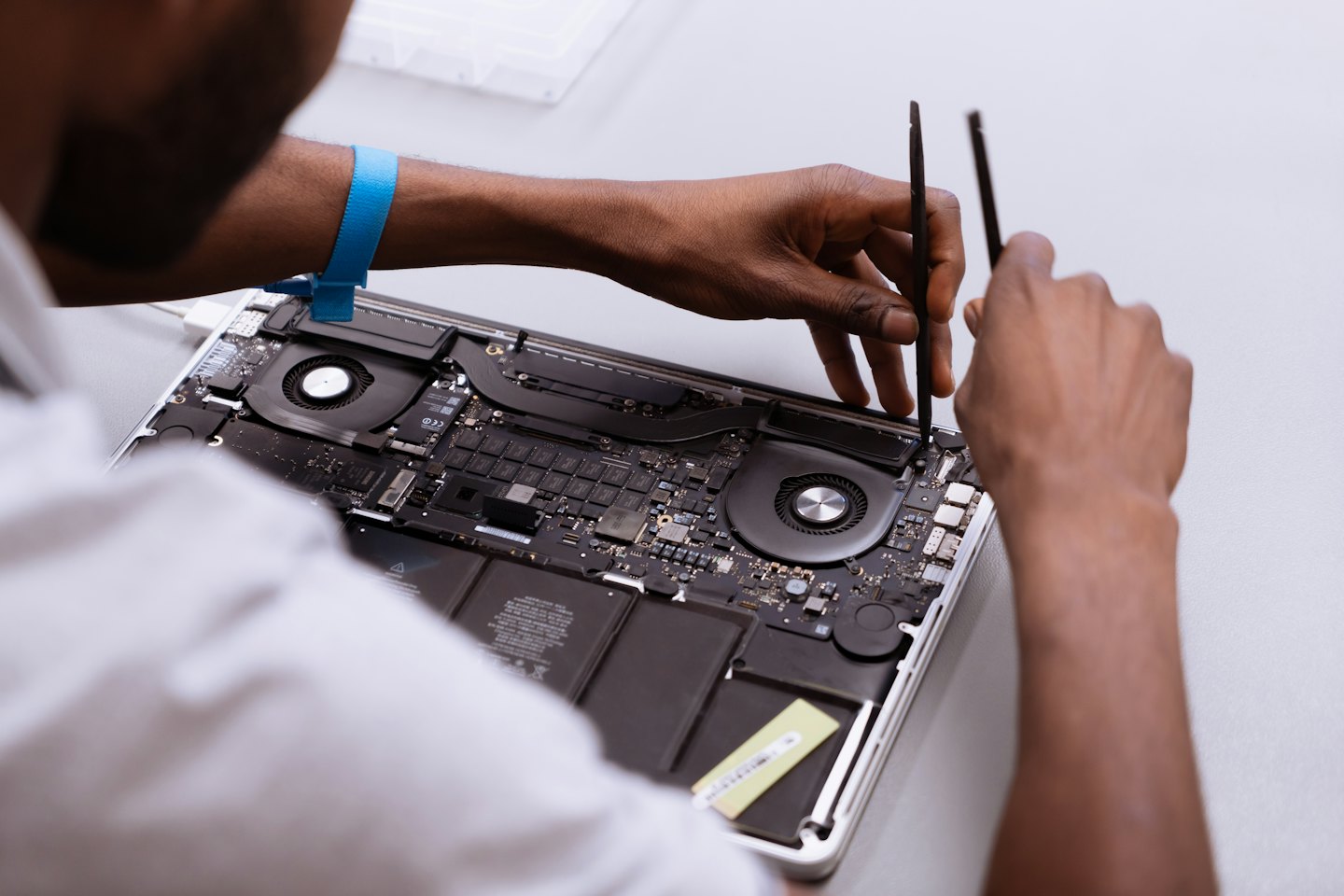 Tecnico ripara un laptop aperto con piccoli attrezzi.