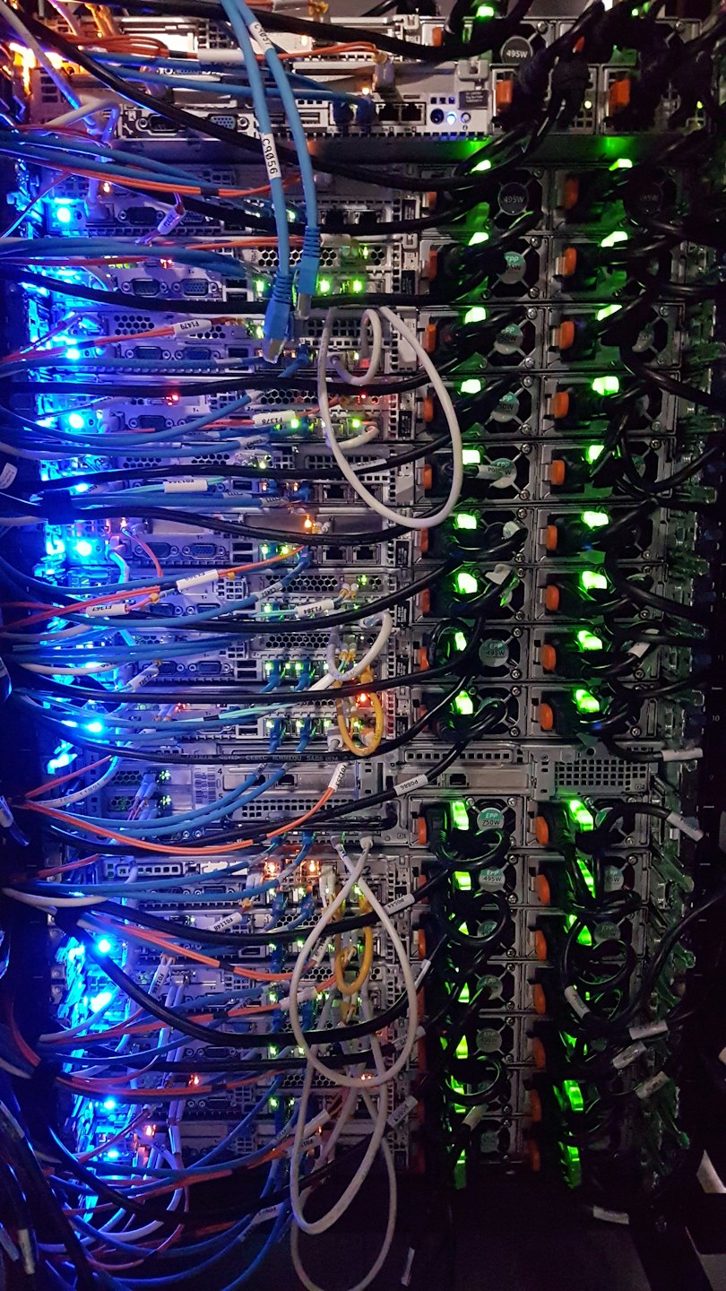 Rack di server con molti cavi colorati e luci lampeggianti.